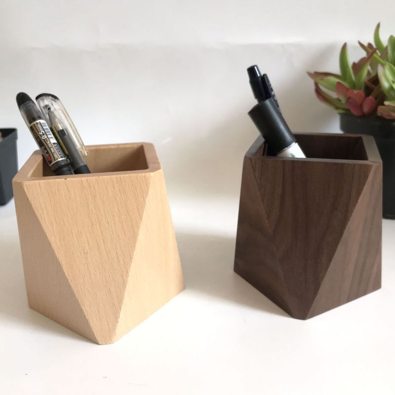 Light beech and dark walnut pen holders with pens and a small succulent plant