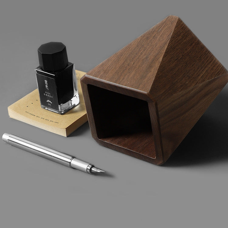 Angled wooden pen holder styled with a fountain pen and ink bottle on a desk
