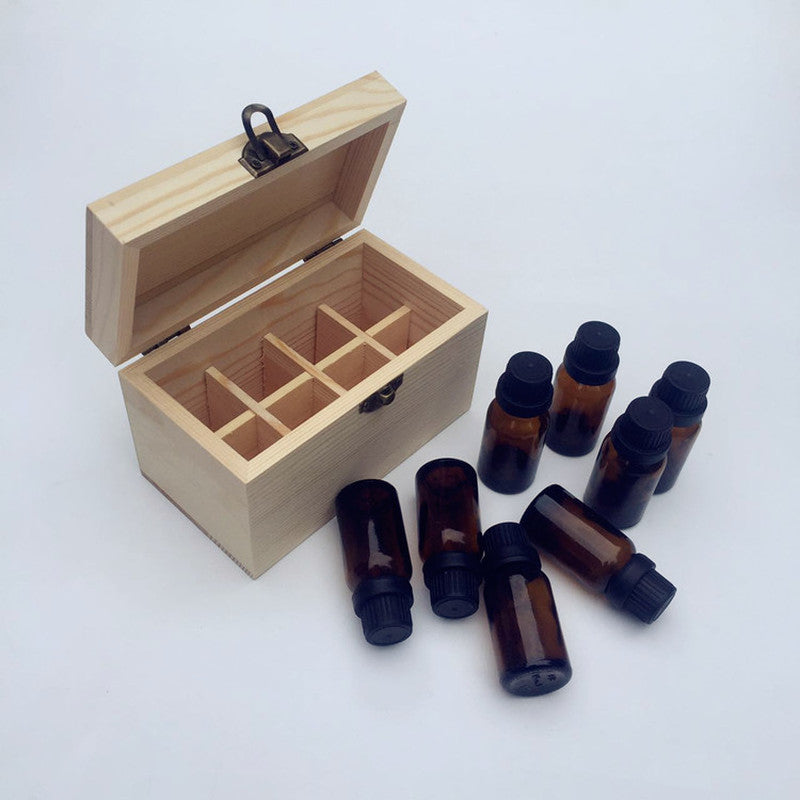 Empty wooden essential oil storage box beside a full set of dark glass essential oil bottles showing compartment scale
