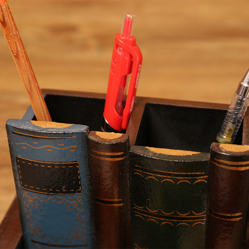 Close-up of book-shaped pen holder compartments beside a small desk lamp