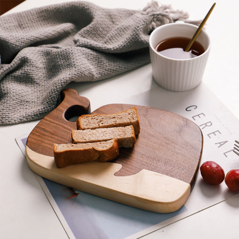 Walnut whale cutting board serving bread slices alongside tea, styled with a cozy throw