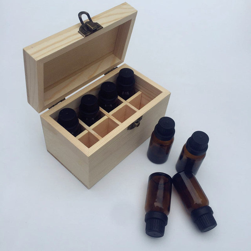 Wooden essential oil storage box partially filled with amber glass essential oil bottles arranged beside it