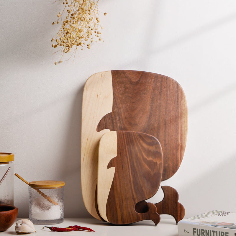 Whale-shaped walnut cutting boards displayed upright on a kitchen counter