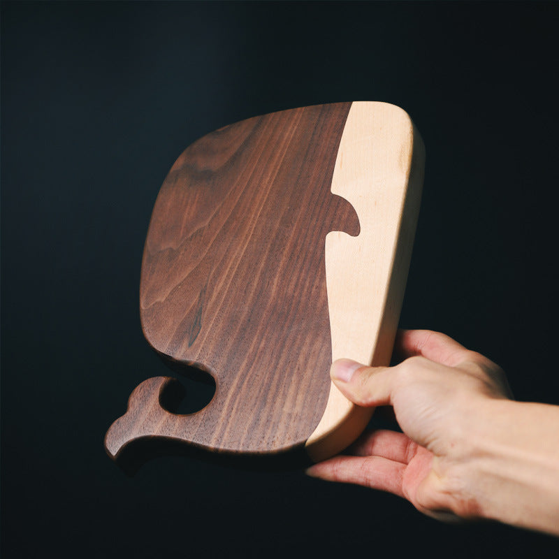 Hand holding a walnut whale cutting board to show scale and craftsmanship