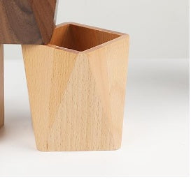 Light beech wood pen holder with angular faceted design on a desk